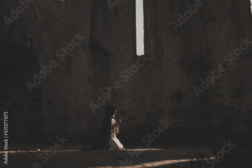 Obraz na płótnie Catholic nun prays in the dark old church