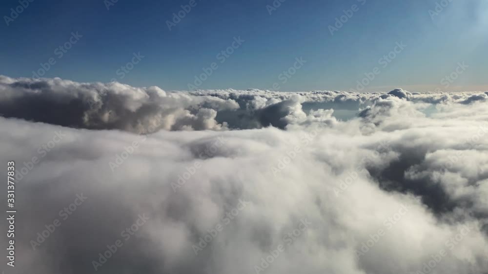 Cinematic shot above bed of white fluffy clouds with bright blue backdrop. Cinematic shot above bed of white fluffy clouds with bright blue backdrop.
