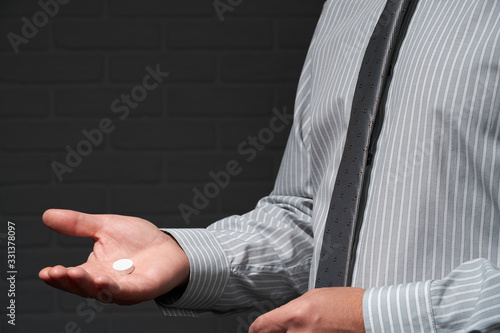 Businessman closeup portrait, he standing and posing with pill, health and medication concept, dark wall background