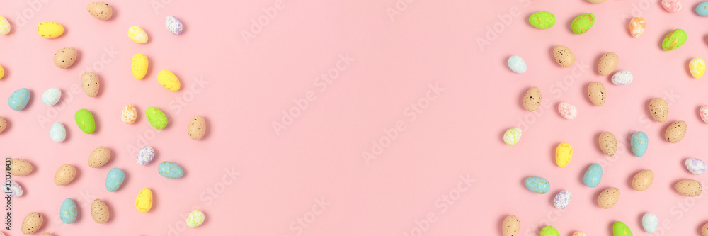 Frame made of colorful easter eggs on a pink pastel background. Holiday creative concept with place for text.