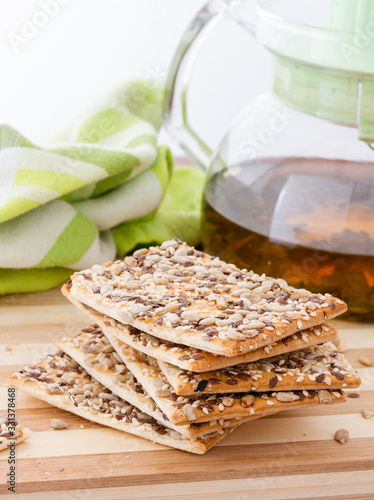 Square crackers with flax, sesame and sunflower seeds on cutting board