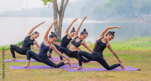 Woman group of  attending a yoga class in a lakeside garden. © udom