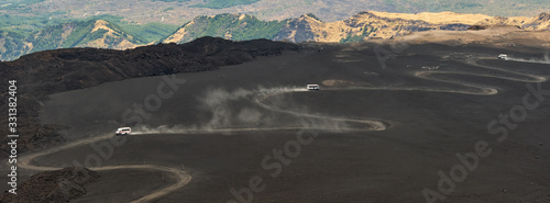 Trucks going up to Etna volcano by winding road, Sicily, Italy photo