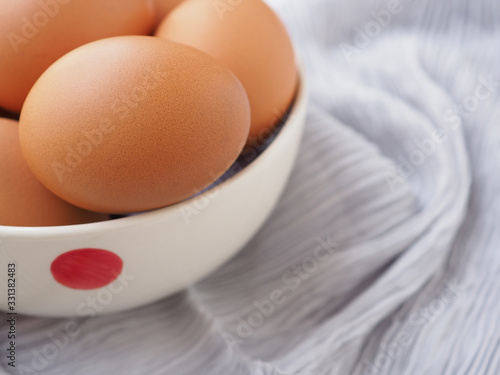 Fresh organic eggs in bowl on grey fabric background. High protein and Vitamin foods. Concept of healthy.