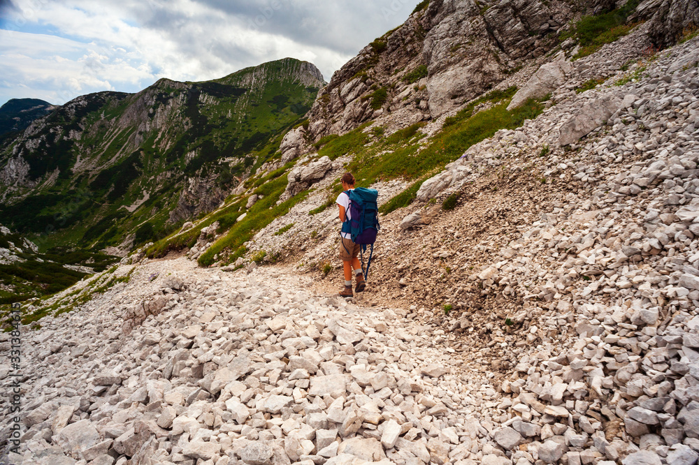 Young woman with backpack hiking along the path in the Vogel mountain, Slovenia