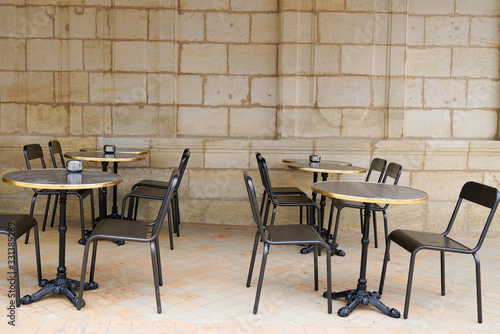 Empty retro tables and chairs on stone building outdoor coffee cafe terrace in Bordeaux France