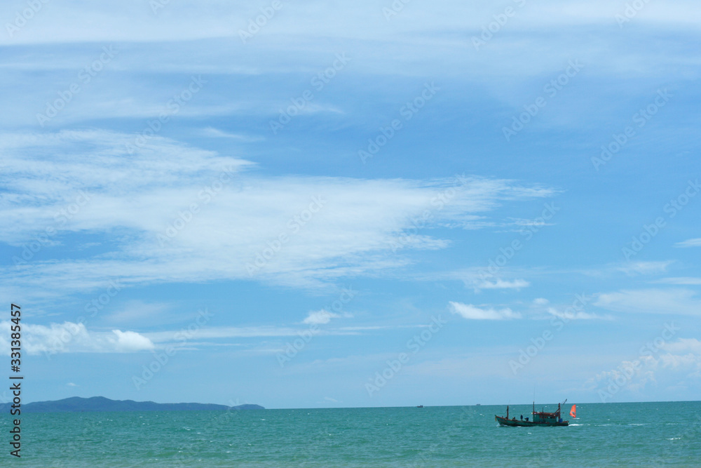 Beautiful marine beach with wooden fishing boat on blue water and sky with fluffy clouds