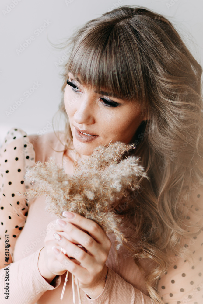 A large portrait of a sensual sexy beautiful attractive curly-haired woman who lies on the bed upside down and plays with dried flowers, the girl poses, laughs and smiles at the camera A large portrait of a sensual sexy beautiful attractive curly-haired woman who lies on the bed upside down and plays with dried flowers, the girl poses, laughs and smiles at the camera