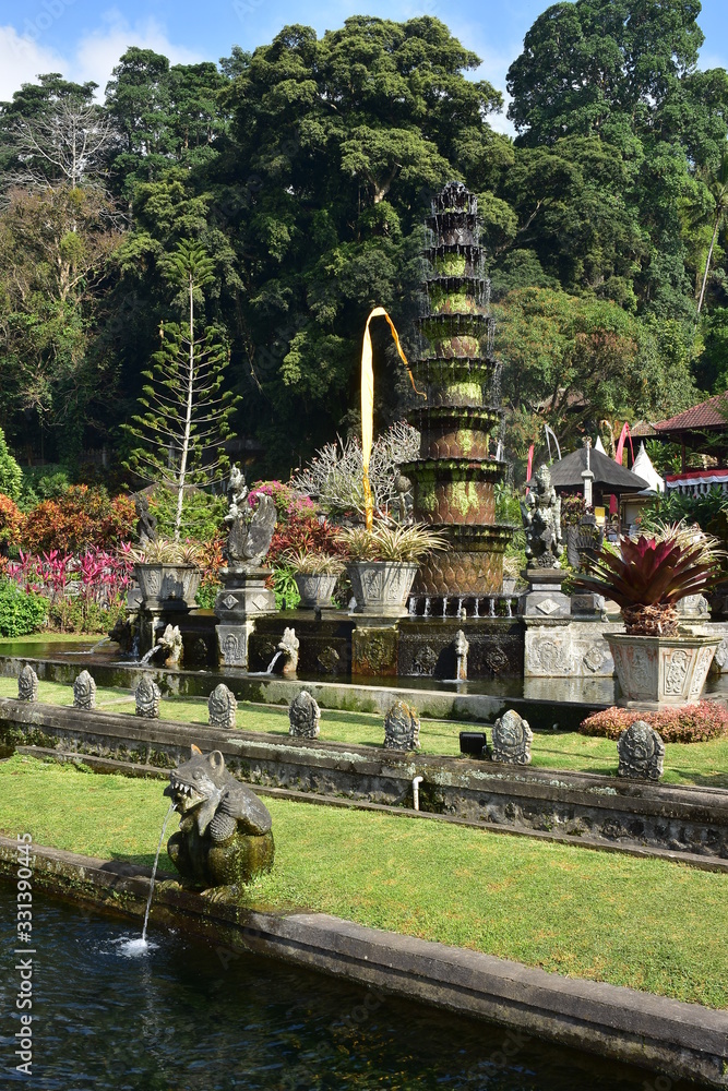 Ornamental garden terraces with stone statues and fountain in Tirtagangga Water Palace in Bali.