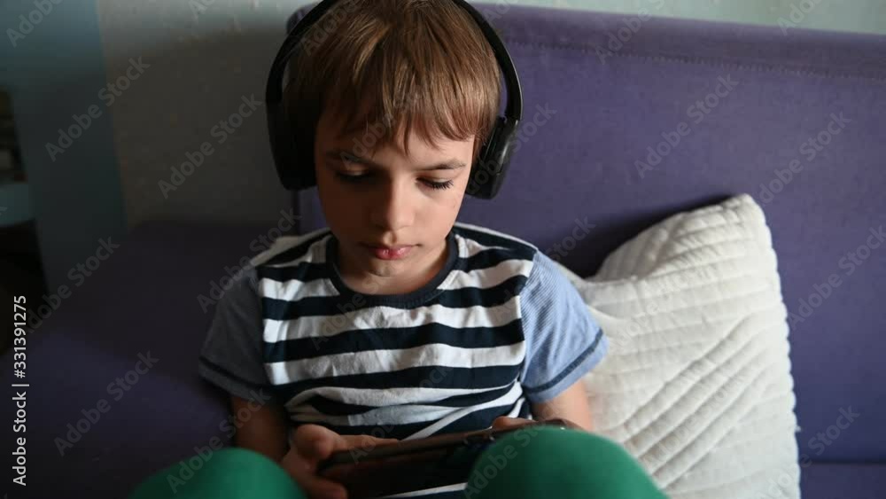 Portrait of a relaxed teenage boy sitting on sofa with smart phone.