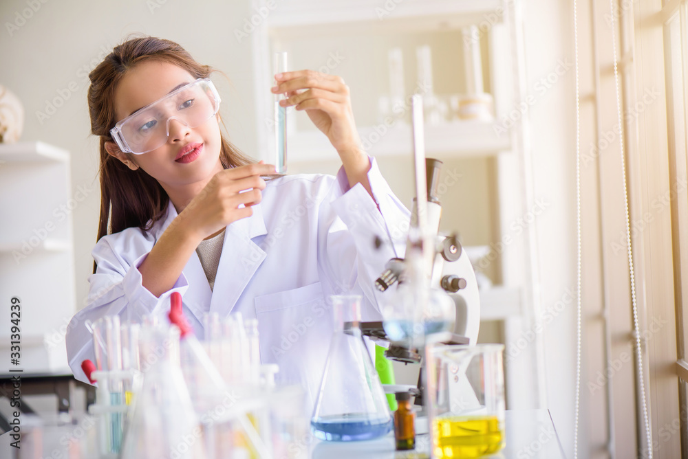 Attractive happiness Scientist woman using microscope testing some blood sample at laboratory with lab glassware on the table. Science or medical research and development new antivirus concept. Attractive happiness Scientist woman using microscope testing some blood sample at laboratory with lab glassware on the table. Science or medical research and development new antivirus concept.
