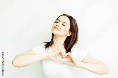 Young girl in a white T-shirt shows a gesture - heart on a white background © Игорь Дзюин