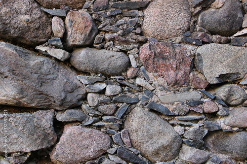 Old wall made of rocks. Medieval surface made of bricks. Texture of an old rocks sticked up with a cement.