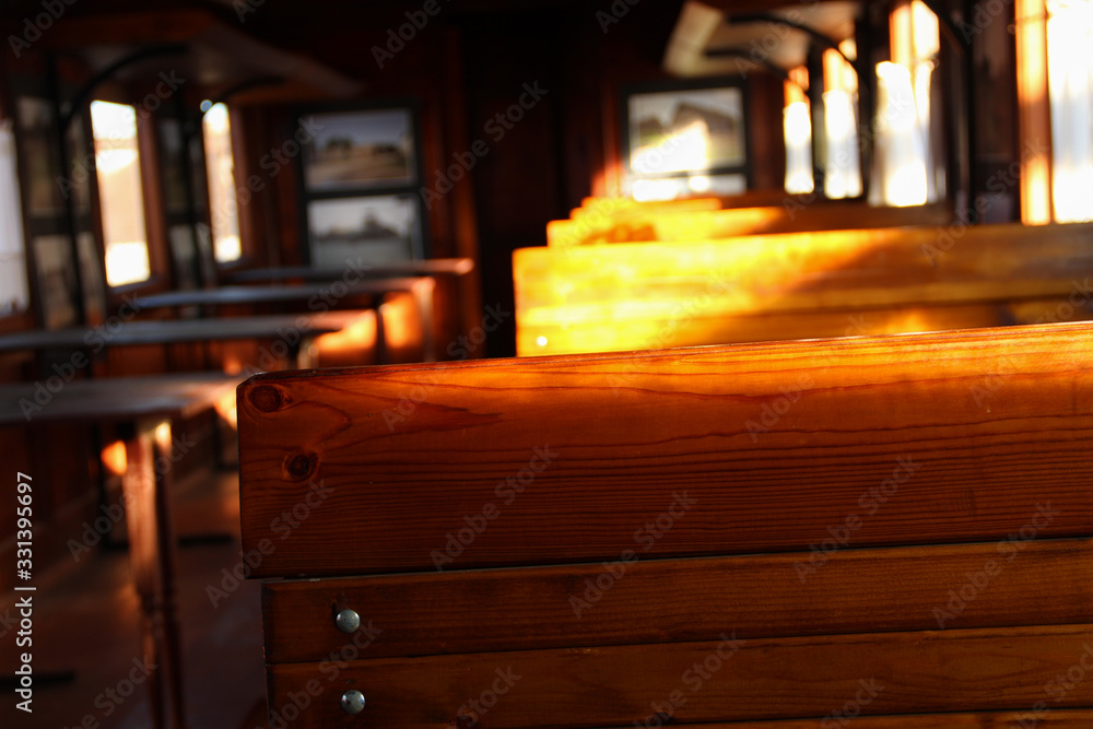 Old wagon interior made of wood. Wooden chairs in an aged train wagon. Abstract traveling background.