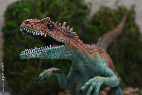 head of a model of a predatory dinosaur on a background of moss
