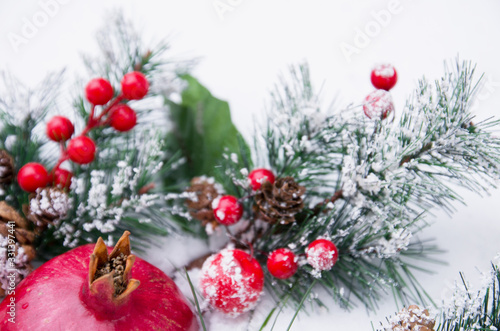 Beautiful Christmas background with pomegranate fruit and fir branches on snow  winter season
