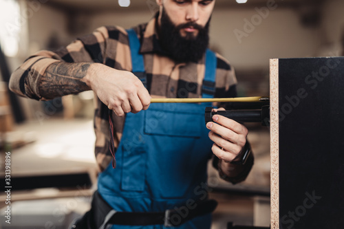 Focused professional carpenter working in his workshop, woodworking and craftsmanship concept.
