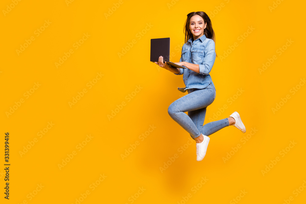 Full length profile photo of funny business lady jump high up hold notebook hands addicted worker always online wear casual denim outfit white sneakers isolated yellow color background - obrazy, fototapety, plakaty 