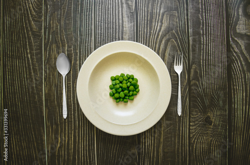 Green bean pea in plate with spoon and fork on wooden table