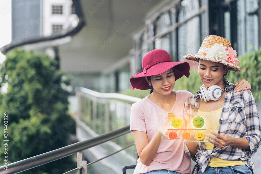 Happy travel together of two fashionable Asian girls giving excellent rating for online satisfaction survey using future technology touch screen interface application, Visual effects. lifestyle