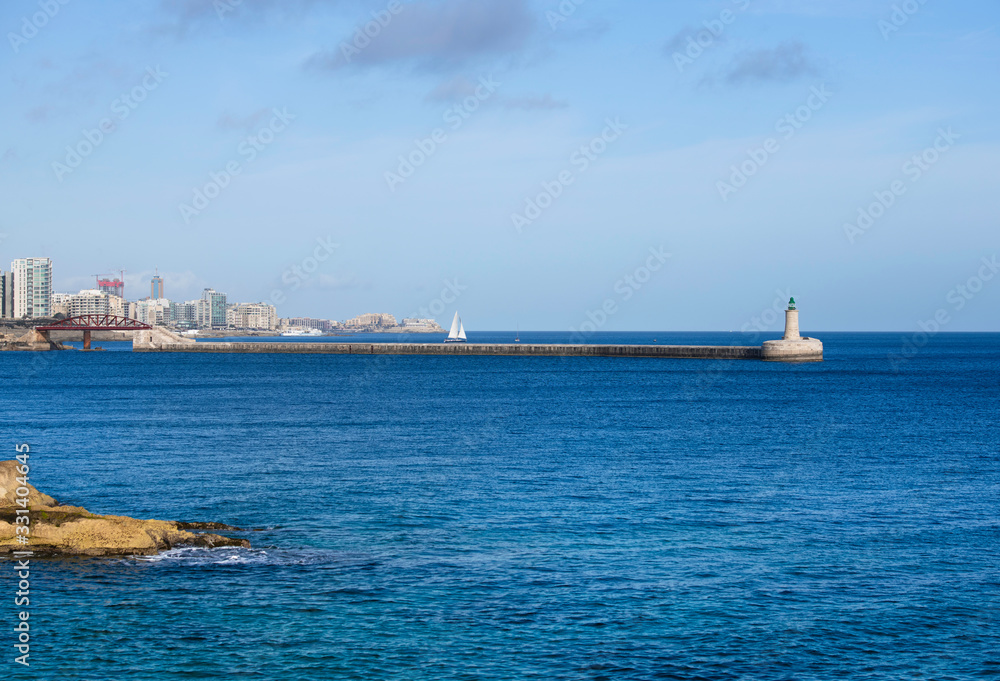 View of the old Saint Elmo Lighthouse, Valletta,Malta,Light tower.St Elmo Bridge or Breakwater Bridge,single-span arched truss steel sea footbridge in Valletta, Malta.Valletta bridge