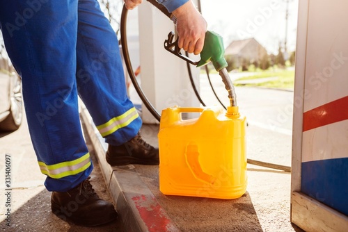 Gas station attendant pouring gasoline into canister. Oil industry concept. photo