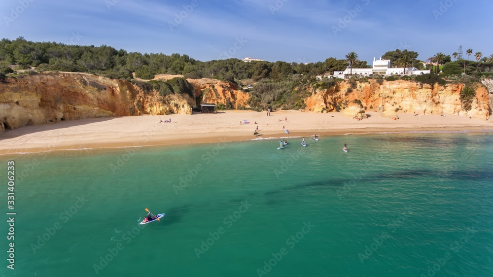 Young people in a practical surfing lesson, stand on the boards with oars. Portugal Algarve.
