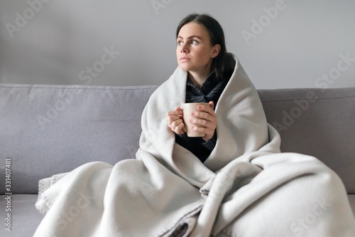 Foto Young woman with cup, sitting at home on sofa