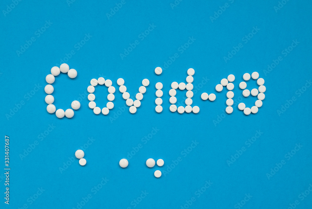 The word COVID-19, laid out with white tablets on a blue background horizontally. Coronavirus, quarantine concept. Selective focus. Horizontal orientation. View from above. The word COVID-19, laid out with white tablets on a blue background horizontally. Coronavirus, quarantine concept. Selective focus. Horizontal orientation. View from above.