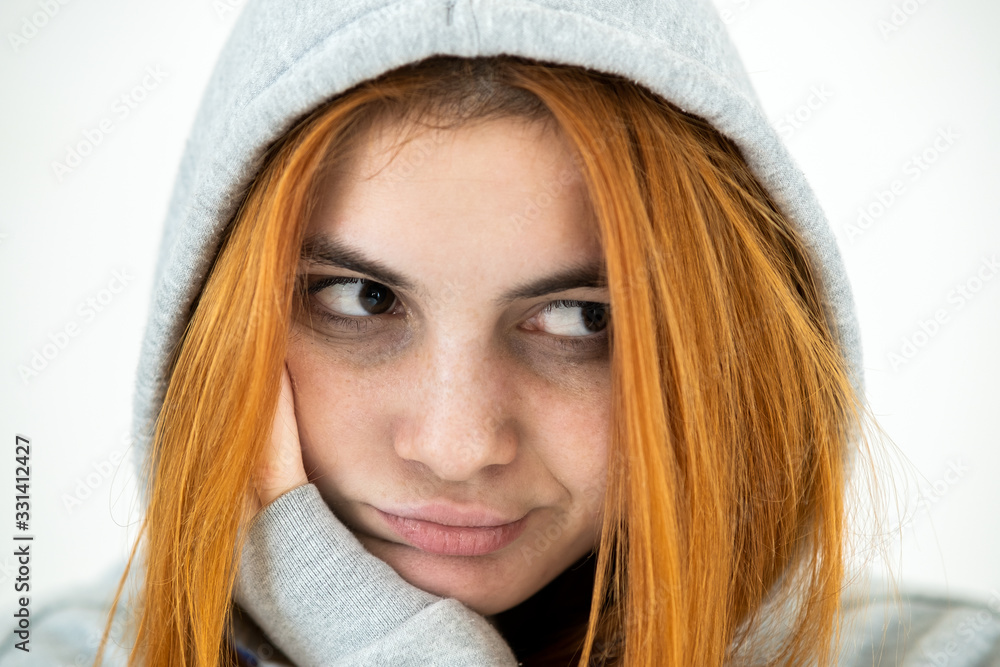 Close up portrait of sad depressed young redhead woman wearing warm hoodie pullover. Close up portrait of sad depressed young redhead woman wearing warm hoodie pullover.