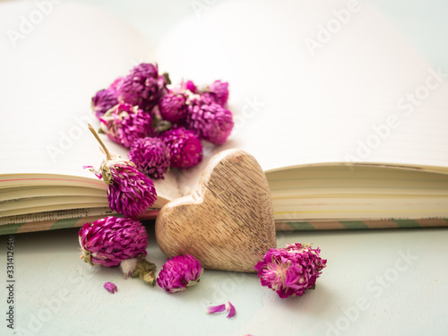 Fototapeta Naklejka Na Ścianę i Meble -  Herz mit lila getrockneten Blüten auf einem offenen Buch, Liebe