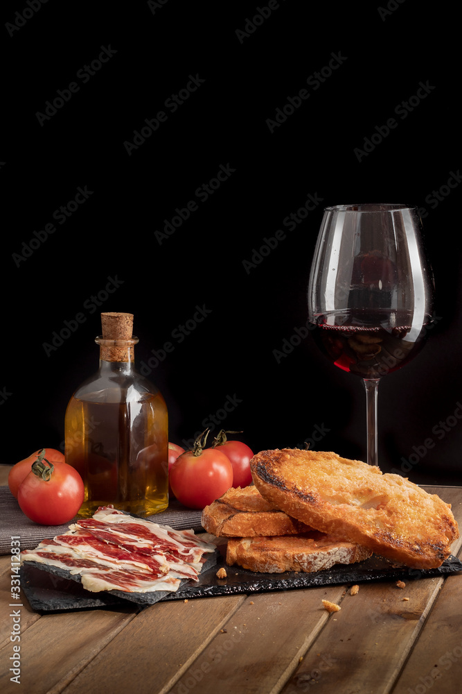 Still life of serrano ham with tomato bread on slate stone tray. black ...