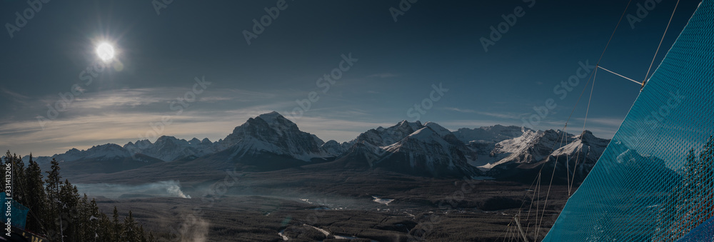 Panoramic view of the rocky mountains lit by winter sun above Lake Louise area, looking from the top of the Lake Louise ski resort. - obrazy, fototapety, plakaty 