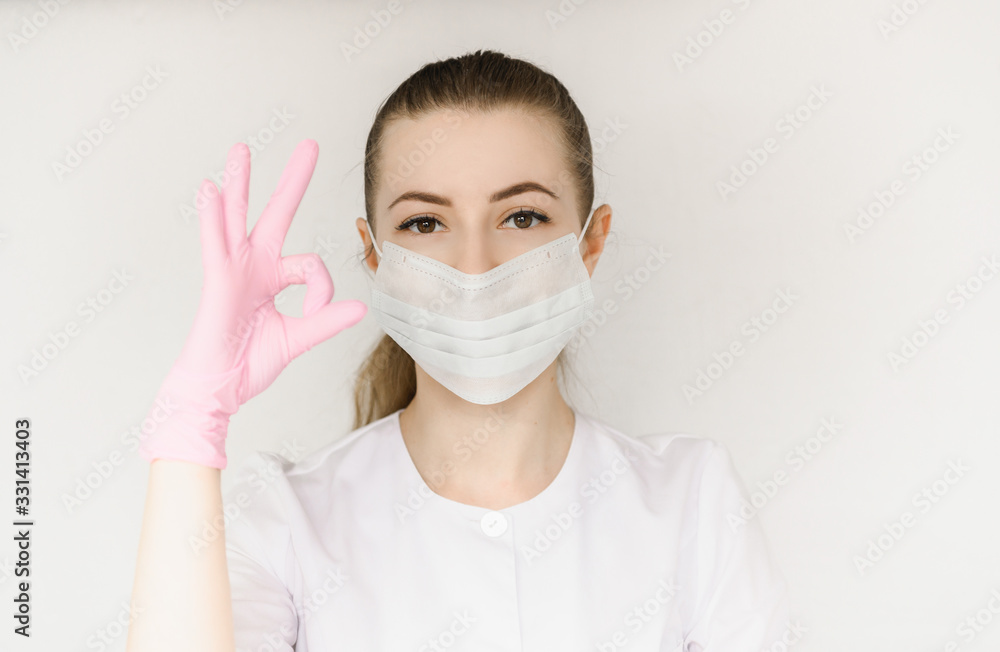young successful girl doctor in protective mask and white coat shows sign with okay hand young successful girl doctor in protective mask and white coat shows sign with okay hand