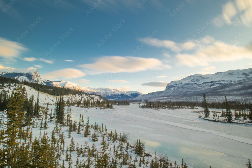 View from the bridge at Saskatchewan river crossing in early morning winter hours. Sun just rising behind the hills, frozen river seen in the foreground.