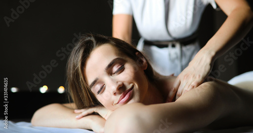 Happy woman relaxing receiving a massage in a spa salon