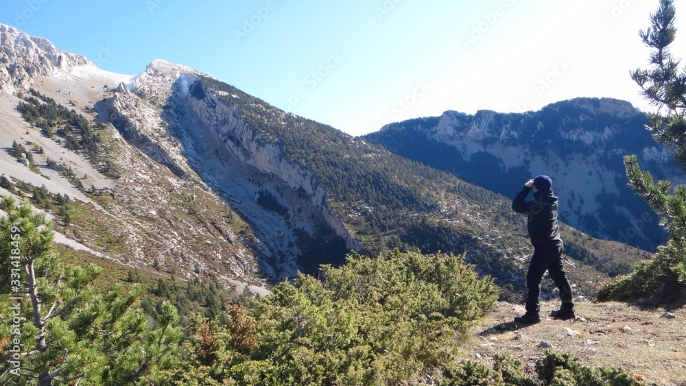 Bosque en una montañas, la silueta del cielo, un hombre mirando y reflejo del sol