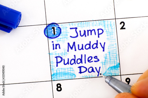 Valokuva Woman fingers with pen writing reminder Jump in Muddy Puddles Day in calendar