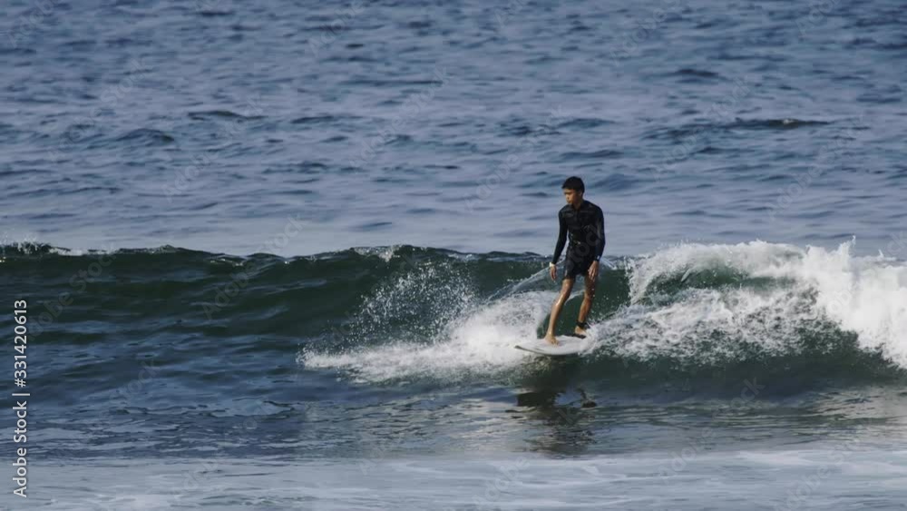 Long lens close up shot of a young man surfing a green wave in Indonesia, Java Long lens close up shot of a young man surfing a green wave in Indonesia, Java