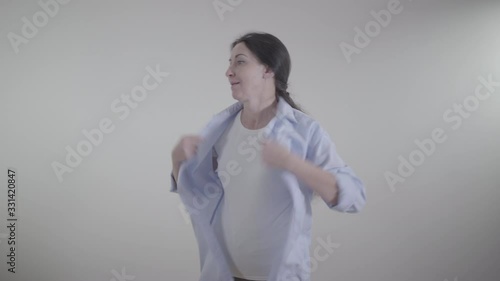 Portrait of Caucasian woman feeling hot indoors. Brunette lady shaking clothes and waving hands on face to cool down. Temperature, season, lifestyle.
