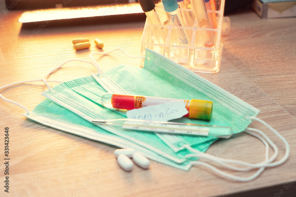 Medical face mask and pills with inscription Wuhan coronavirus 2019-nCoV on yellow table background. Novel coronavirus COVID-19 concept. Medical face mask and pills with inscription Wuhan coronavirus 2019-nCoV on yellow table background. Novel coronavirus COVID-19 concept.