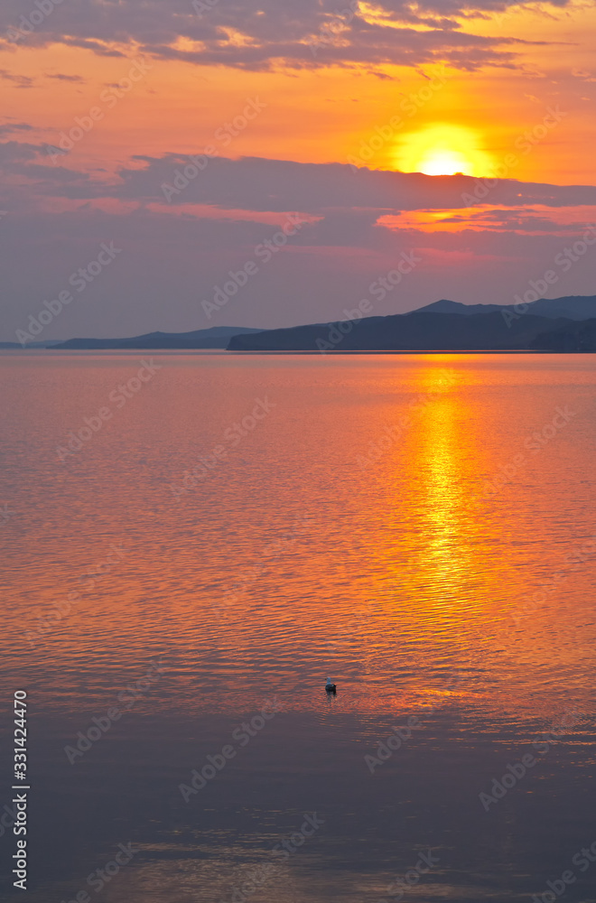 Baikal  Lake in spring morning. Beautiful bright sunrise is reflected in the water of the Small Sea Strait. Dawn waterscape. Natural background