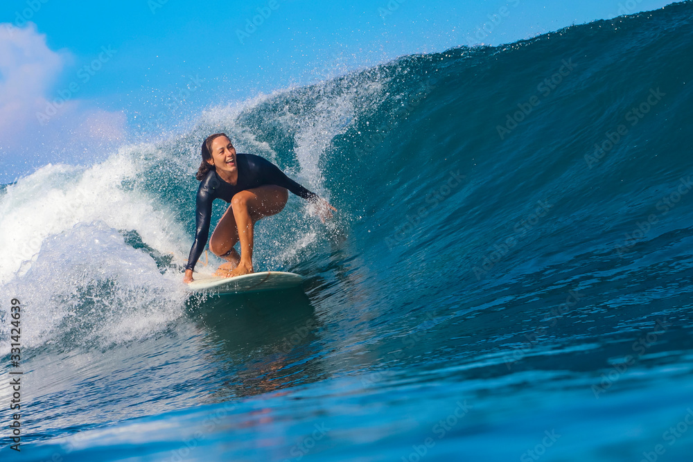 Female surfer on a blue wave - obrazy, fototapety, plakaty 
