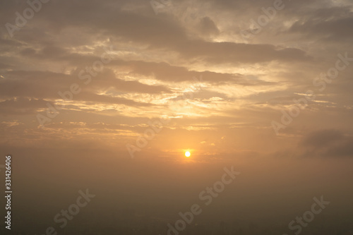 Beautiful sunset scene above the building, orange light and the mist cover all over the city © Arunee