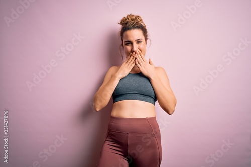 Young beautiful blonde sportswoman doing sport wearing sportswear over pink background laughing and embarrassed giggle covering mouth with hands  gossip and scandal concept