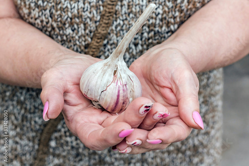 Senior woman holds garlic in hands. The concept of a healthy diet, strengthening immunity