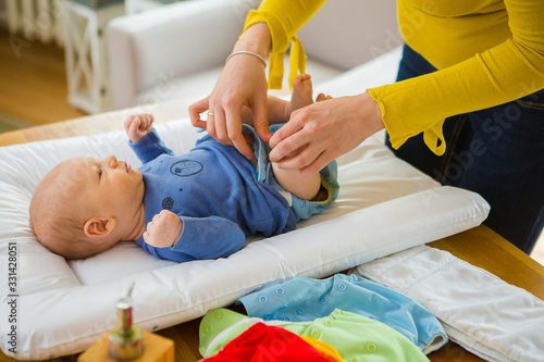Mother changing reusable diaper or nappy. Reusable diaper and infant. Baby with eco diaper. 