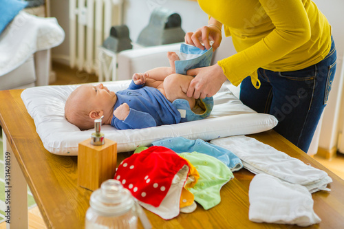 Mother changing reusable diaper or nappy. Reusable diaper and infant. Baby with eco diaper. 