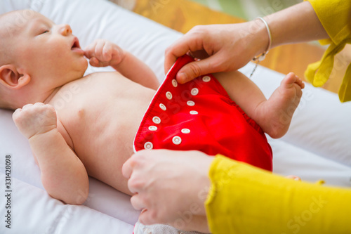 Mother changing reusable diaper or nappy. Reusable diaper and infant. Baby with eco diaper. 