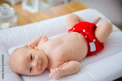 Mother changing reusable diaper or nappy. Reusable diaper and infant. Baby with eco diaper. 